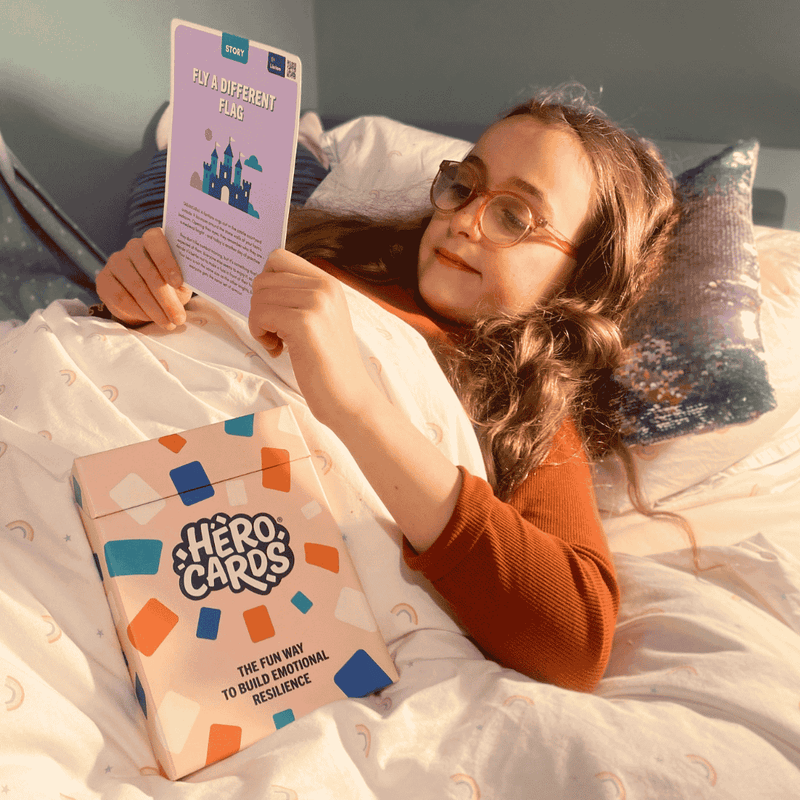 Child reading a story from Hero Cards while getting ready to go to sleep, in bed.
