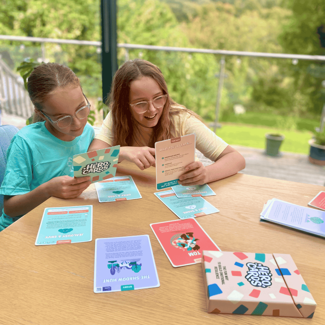 Two young girls using Hero Cards with a scenic background