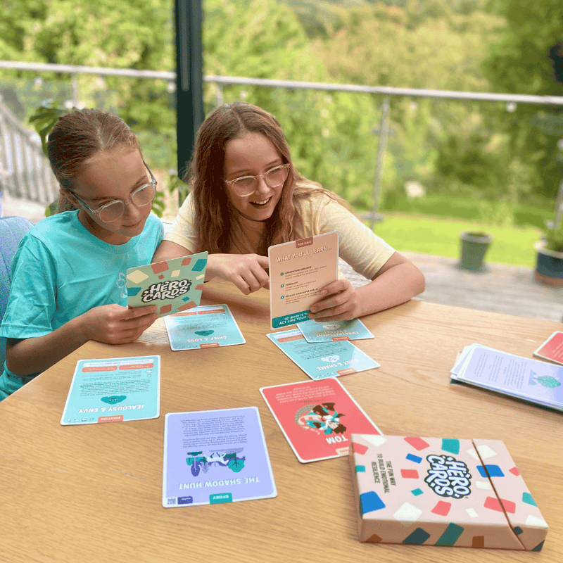 Two young girls using Hero Cards with a scenic background