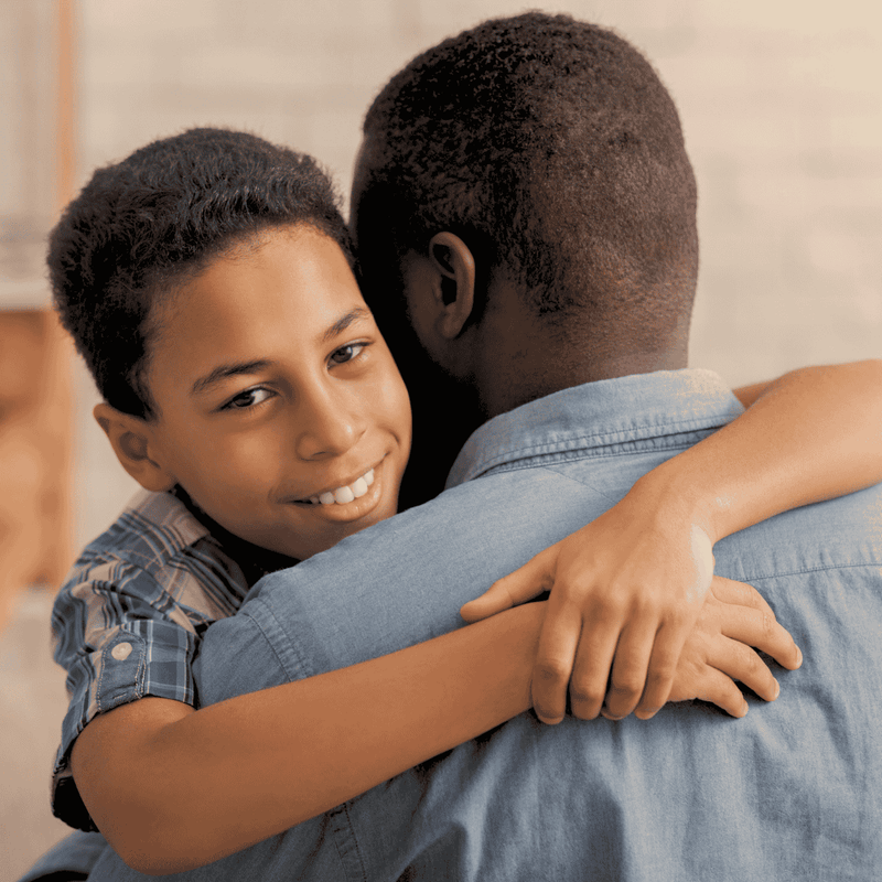 Child hugging an adult with a neutral background