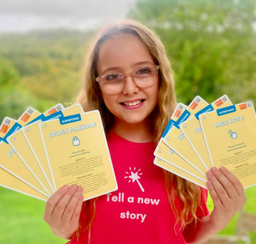 Girl holding yellow superpower cards with text and graphics, outdoors